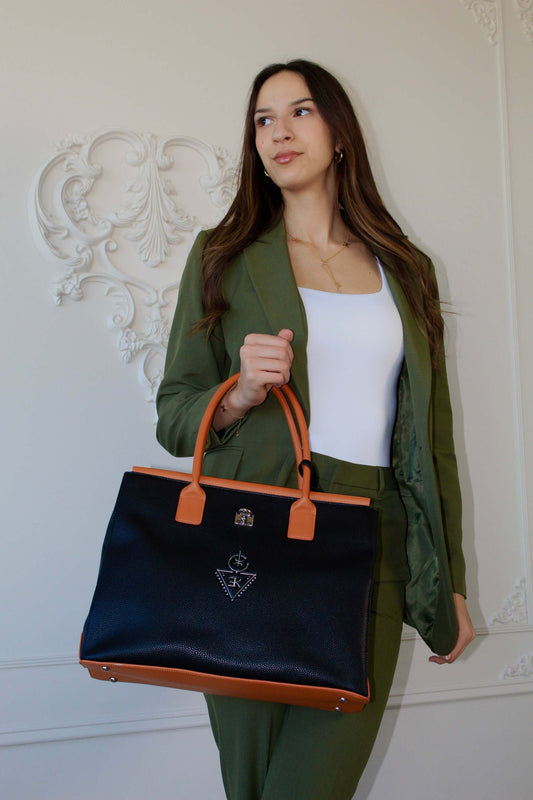 Sac fourre-tout THILLELI noir avec ganses brunes porté par une femme élégante en costume vert