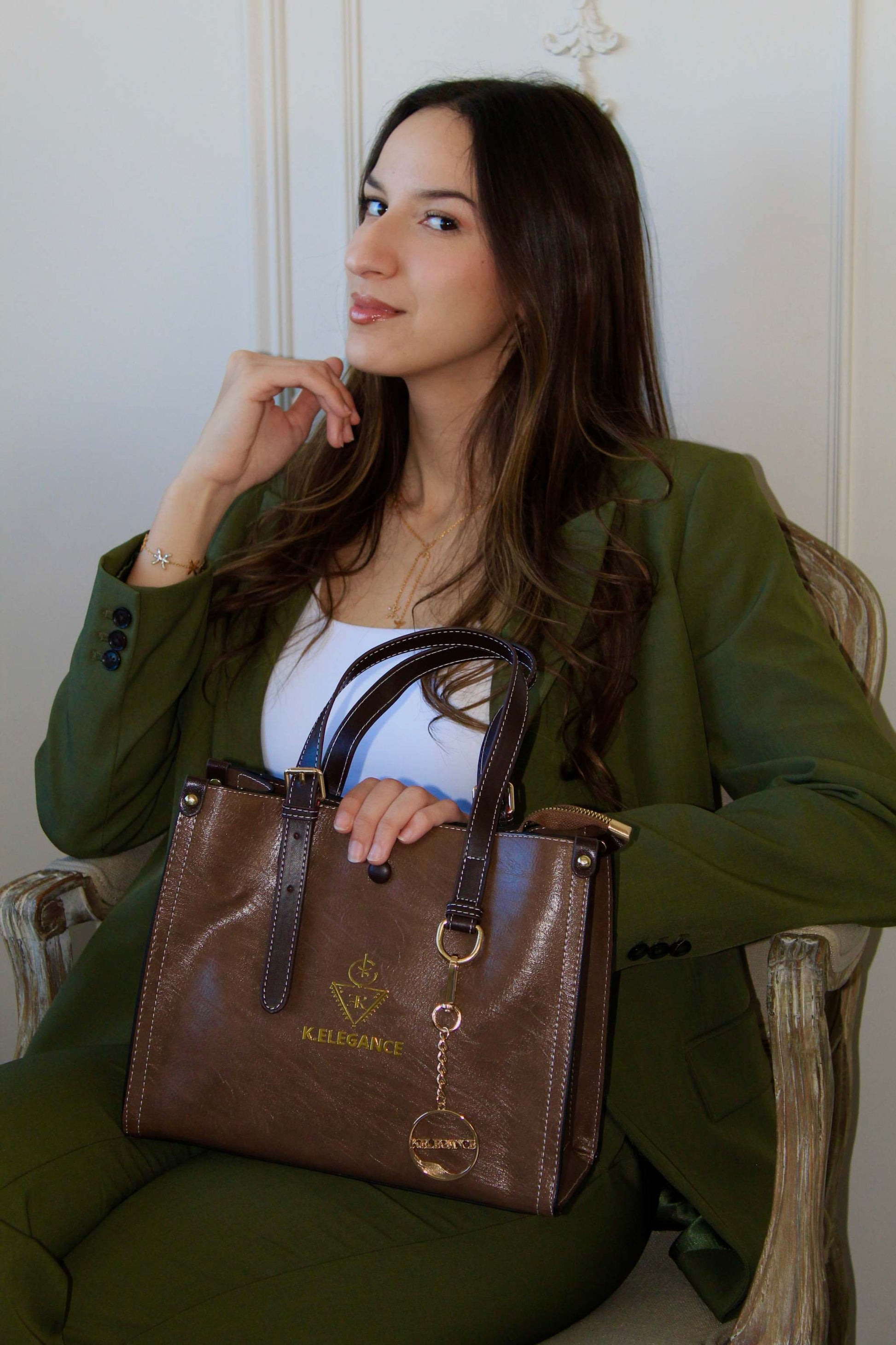 Sac AGGOURI brun chocolat de taille moyenne avec logo doré K.Élégance, posé sur une personne en costume vert.